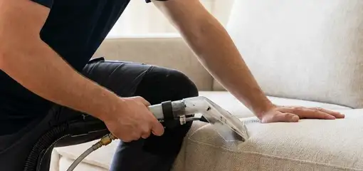 Professional upholstery cleaner deep-cleaning a fabric sofa with a handheld extraction tool, Pasadena, CA.